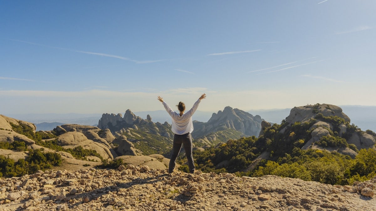 a person standing on top of a mountain with their arms in the air